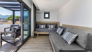 A modern bedroom with a large bed, a sofa, and a balcony with a view of the mountains. - Anassa Suites (Dio-Olympos)
