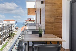Un balcón con mesa y sillas de madera, con vistas a una zona residencial y al mar.