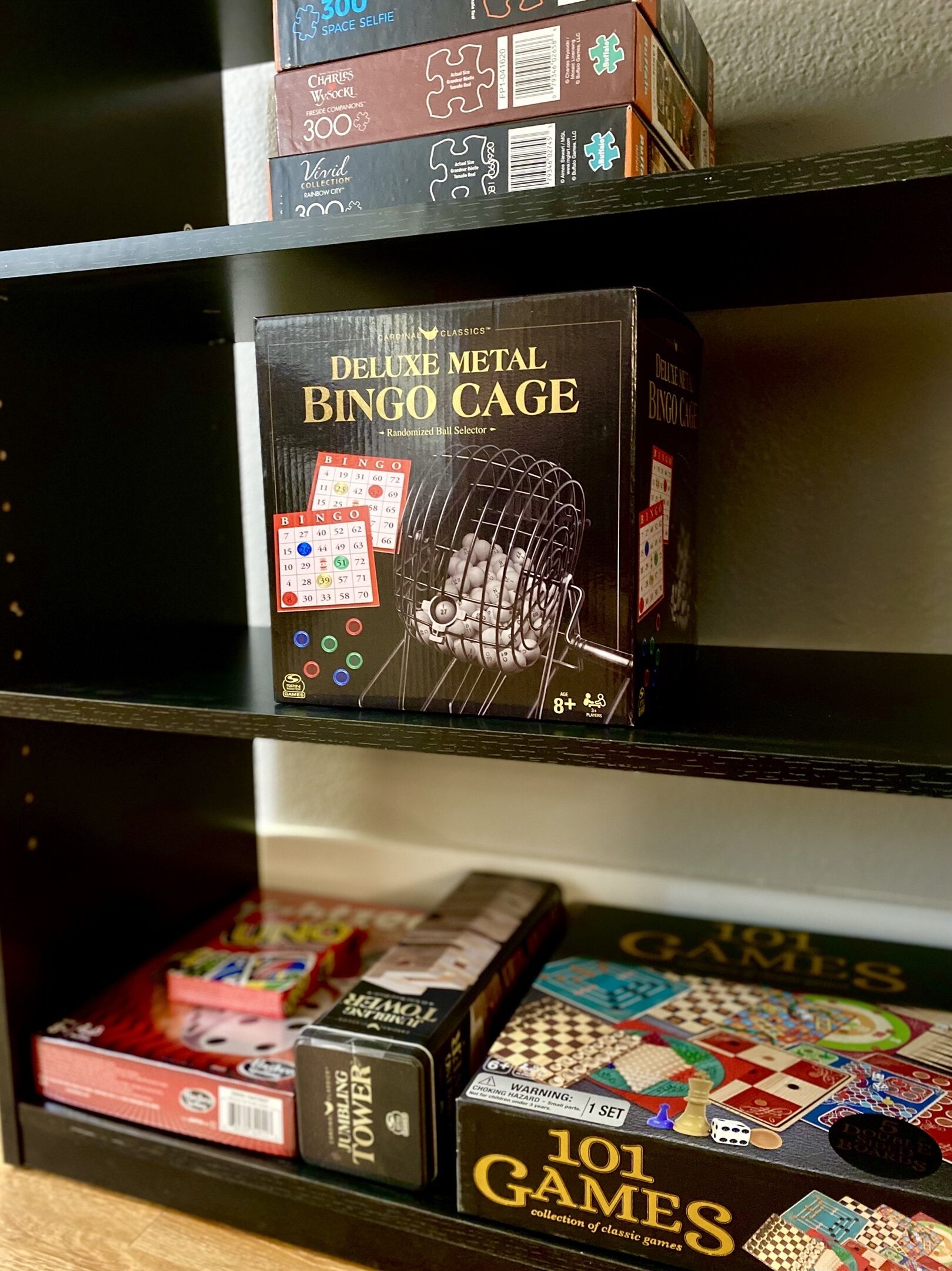 Ein Regal mit verschiedenen Gesellschaftsspielen, darunter ein Bingozug aus Metall und eine Sammlung mit 101 Spielen.