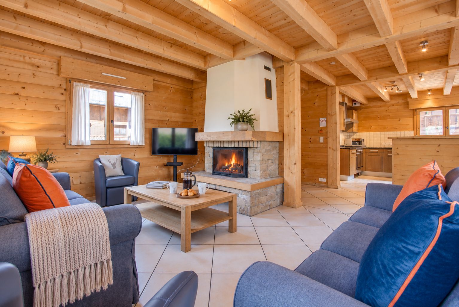 A cozy log cabin interior with a fireplace, a television, and a dining area.