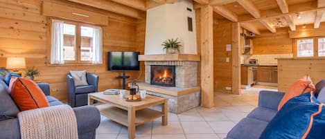 Un acogedor interior de cabaña de madera con chimenea, televisor y comedor.