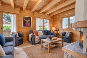 A cozy log cabin interior with a fireplace, wooden walls, and a sofa set.