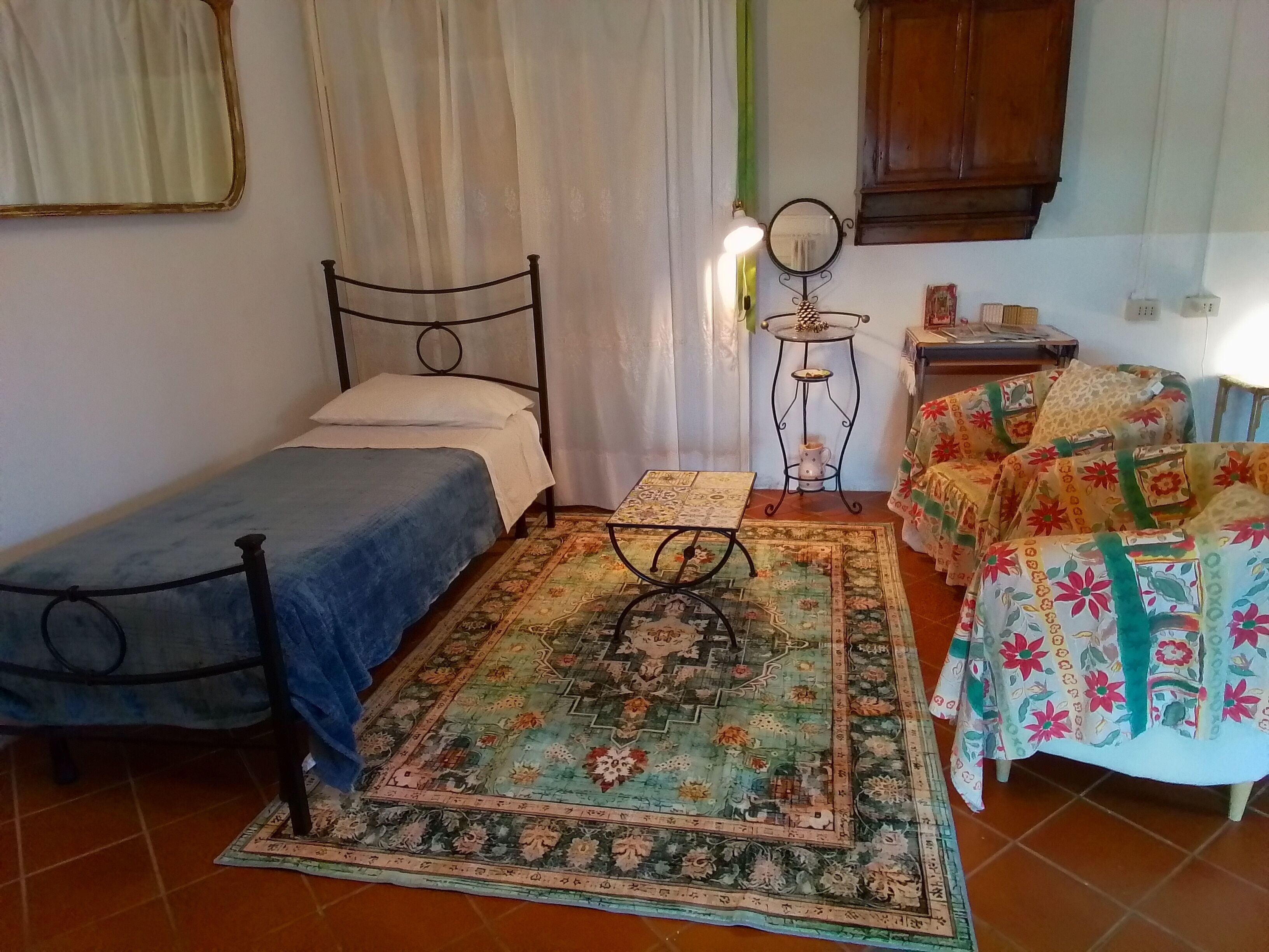 Une petite pièce agréable et chaleureuse, avec un lit simple, une petite table, une chaise et un tapis décoratif.