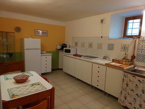 Une cuisine de taille réduite équipée d’un réfrigérateur, d’un four à micro-ondes et d’un plan de travail recouvert de carreaux.