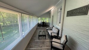 En overdækket terrasse med siddepladser, et bord og et skilt med teksten "THE PORCH".