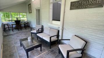 A covered patio area with outdoor seating, a sign reading "THE PORCH," and a view of the outdoors.
