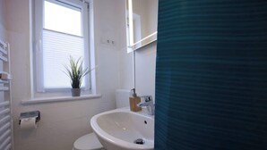 Un baño con inodoro, lavamanos, ventana y radiador.