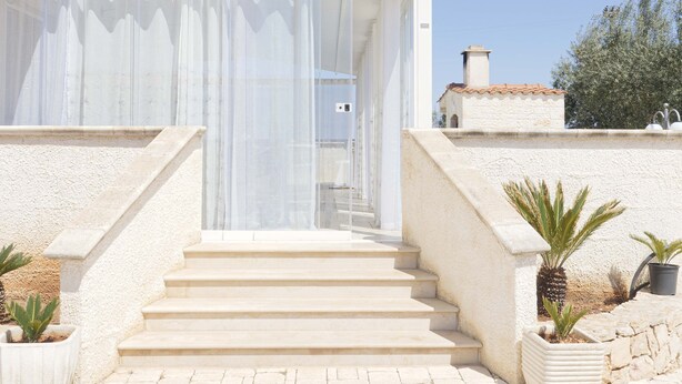 A house with a covered outdoor staircase leading to a door with a white curtain. - Apulian Villa (Conversano)