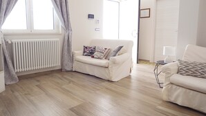 A modern living room with a beige sofa, a white radiator, and a wooden floor. - Apulian Villa (Conversano)