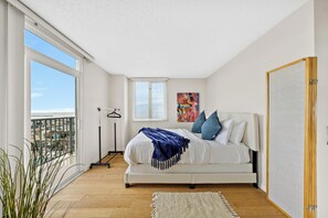 Une chambre à coucher avec un lit, une fenêtre, un tableau et une vue sur la ville.