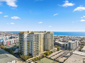 Un immeuble résidentiel de grande hauteur doté de nombreux balcons, d’un terrain de sport sur le toit et offrant une vue sur la mer.
