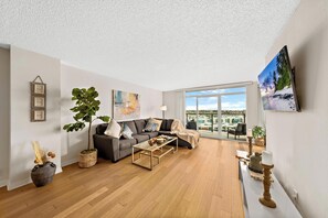 Una sala de estar moderna con sofá, mesa de centro y ventanas amplias con vista a la ciudad.