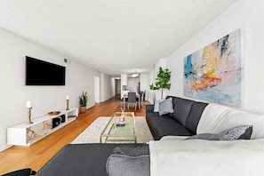 A modern living room with a sofa, coffee table, and TV. There is a dining area in the background. - The Tulip-Oceanview stay highrise-pool,hot thub&parking (Marina del Rey)