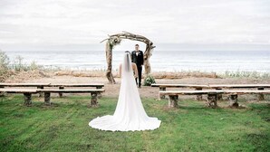 Une cérémonie de mariage sur la plage, avec une arche en bois et des bancs.