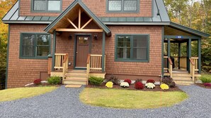 A two-story house with a front porch, a covered entryway, and a small garden with colorful flowers.
