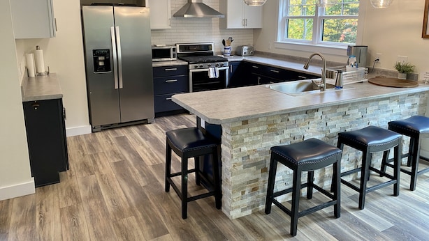 A modern kitchen with a central island, stainless steel appliances, and a stone backsplash.