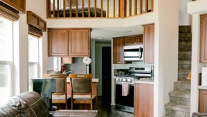 A spacious living area with a high ceiling, a wooden staircase, and a kitchen with modern appliances. - Beachfront House- The Sea Eagle (Sekiu)