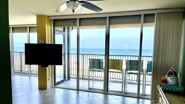 A hotel room with a large balcony, a ceiling fan, and a television. - Fabulous 5th floor beachfront; fully appointed; discount for weekdays & 7 nights (South Padre Island)