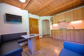 A modern kitchen with wooden cabinets, a built-in oven, and a dining area with a bench and table.