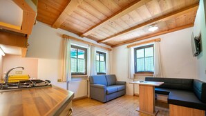 Une cuisine de taille réduite avec un plancher en bois, un canapé gris et une petite table.