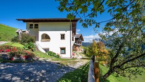 Un bâtiment blanc avec un toit en pente, un espace extérieur couvert et une vue sur les montagnes.