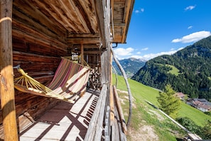 A wooden cabin with a hammock on the porch overlooking a mountainous landscape. - 117B Holiday Farm Tuene (Ortisei)