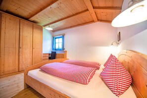 A wooden room with a bed, a desk, and a window.