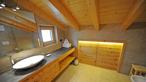 Une salle de bain moderne avec un meuble-lavabo en bois, un grand lavabo et un espace douche.