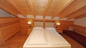 Une chambre dans une cabane en bois, avec un lit, deux tables de chevet et un banc.
