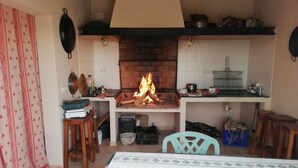 Una cocina con chimenea de ladrillo, salpicadero de azulejos y diferentes electrodomésticos.