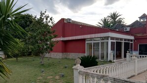 Un patio con un edificio rojo, un balcón blanco y una palmera.