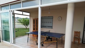 Una habitación con mesa de ping pong, un armario de madera y una silla.