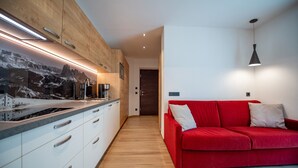 Ett modernt kök med träskåp, en röd soffa och en minimalistisk design.