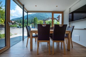 A dining area with a large window, wooden table, and chairs. - 103A Apartments by Cesa Ploner (Ortisei)