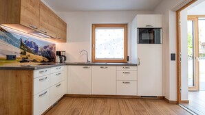 Una cucina moderna con mobili in legno, un forno a microonde integrato e una finestra con persiane.