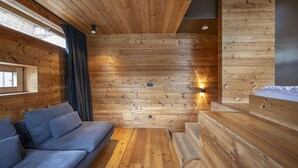 Interior em madeira com sofá, um banco e luminária fixada na parede.