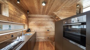 Cozinha moderna com paredes de madeira, eletrodomésticos de aço inoxidável e uma janela grande.