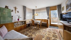 Ein gemütliches Wohnzimmer mit einer Couch, einem Esstisch und einem Fernseher.
