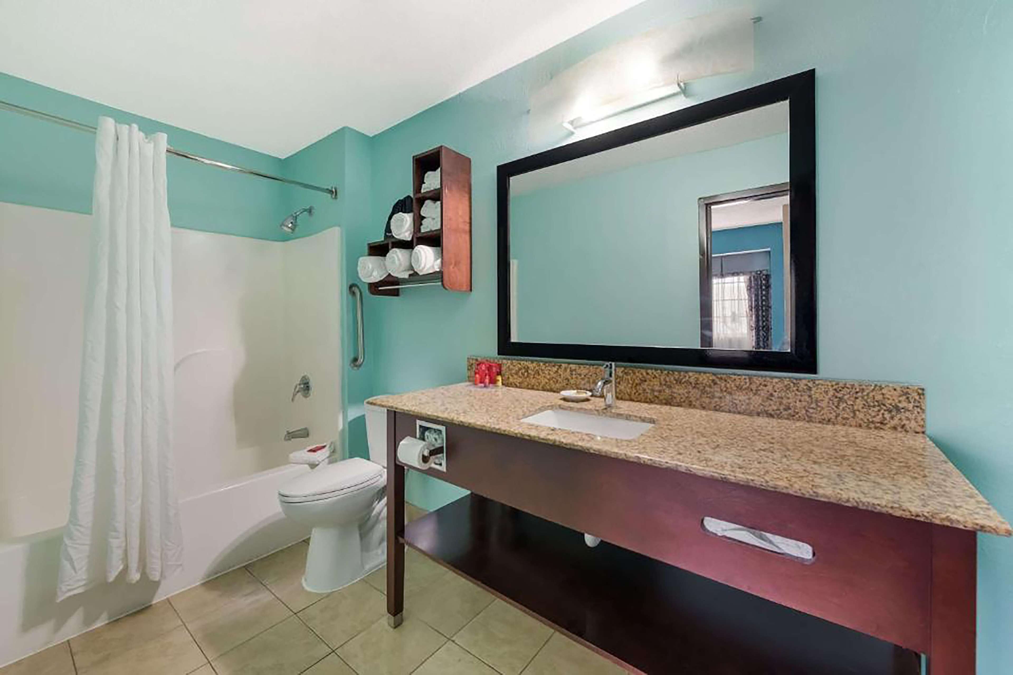 A bathroom with a bathtub, toilet, sink, and a large mirror.