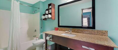 A bathroom with a bathtub, toilet, sink, and a large mirror.