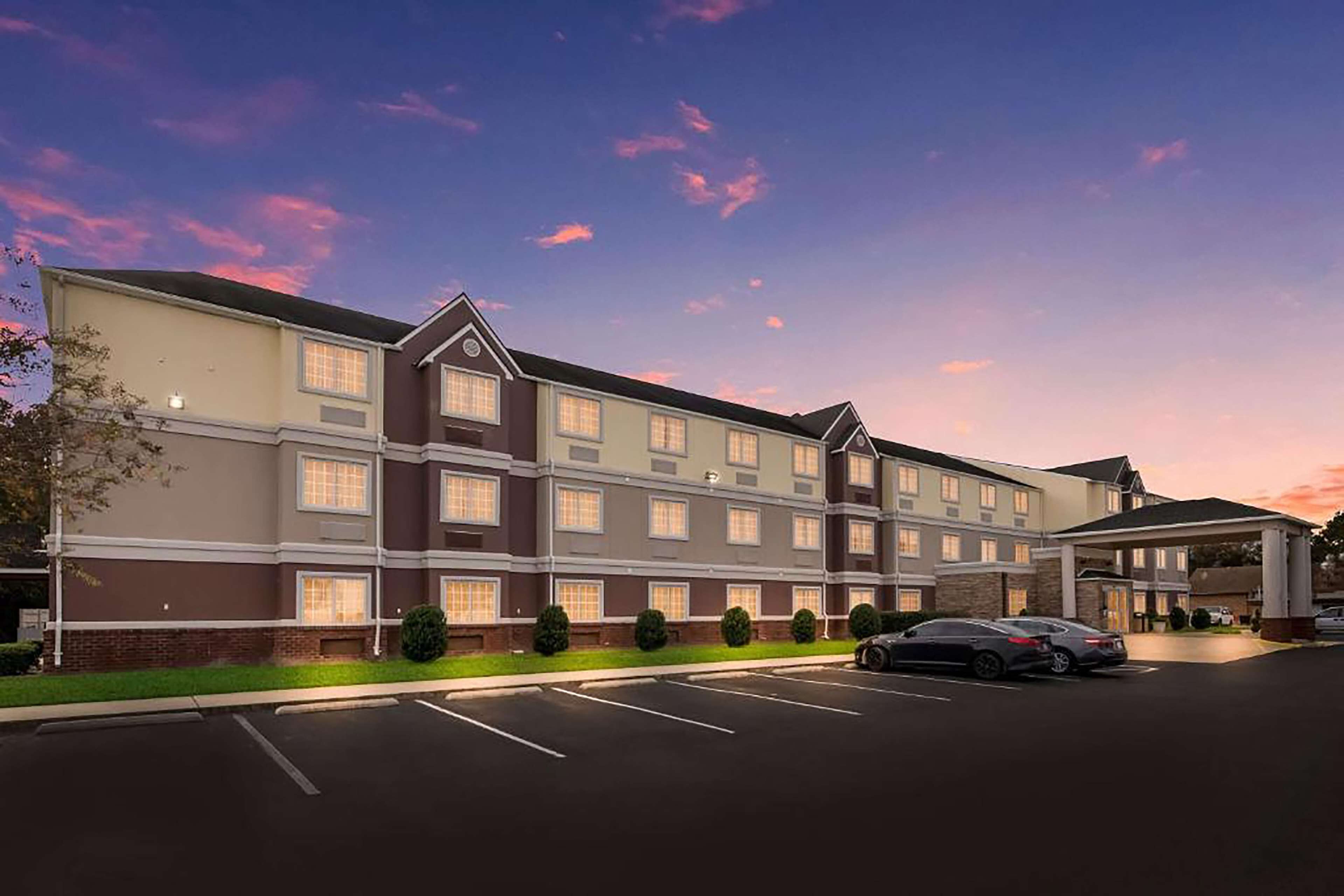 A multi-story hotel with a parking lot and a covered entrance.