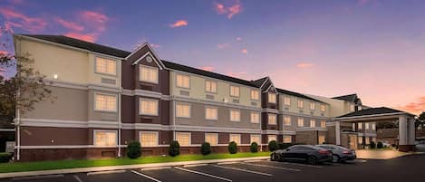A multi-story hotel with a parking lot and a covered entrance.