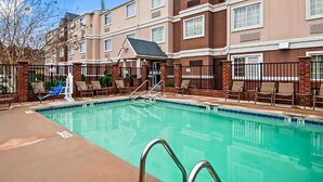 A swimming pool with a 5 ft depth marker, surrounded by lounge chairs and a brick wall. - Baymont by Wyndham Elizabeth City (Elizabeth City)
