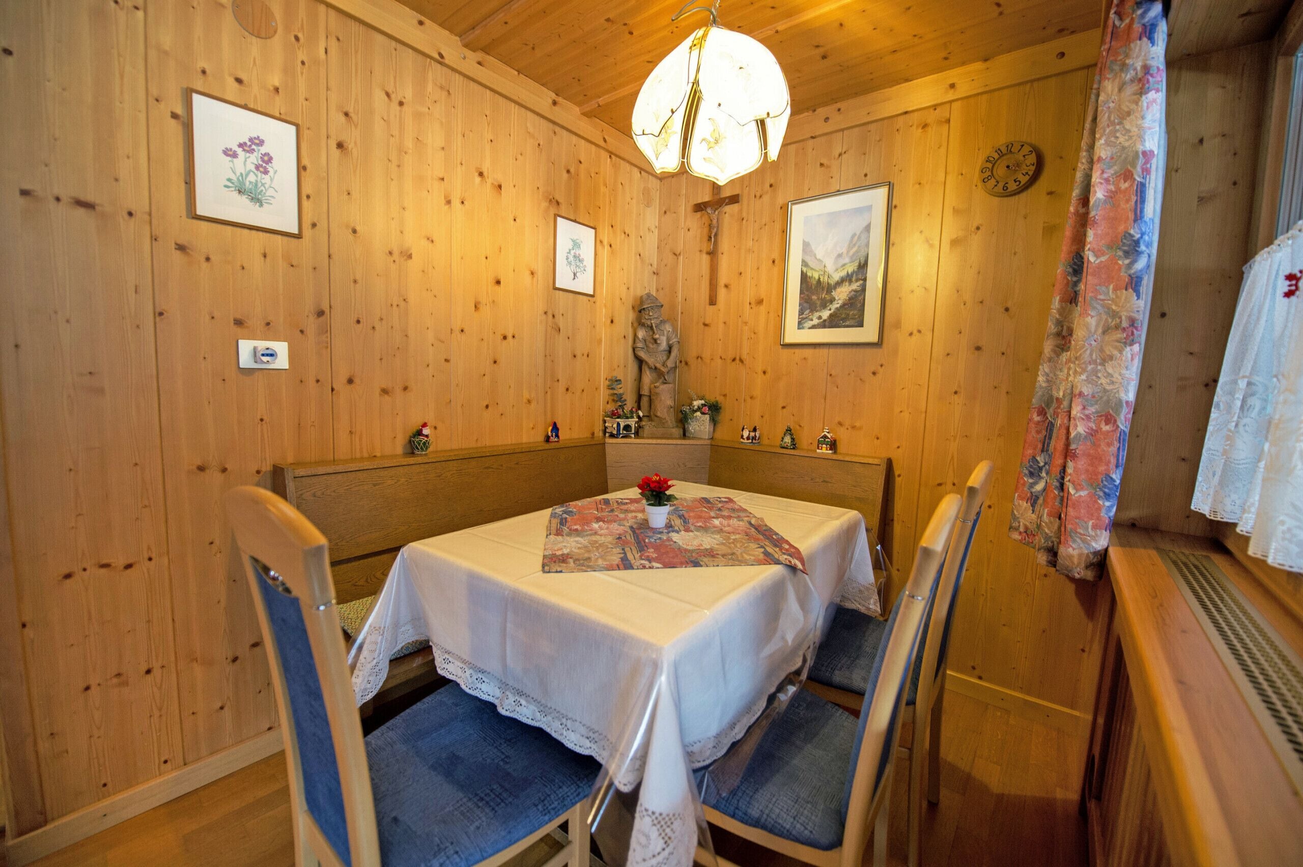 A wooden interior with a dining table set for four, surrounded by chairs.