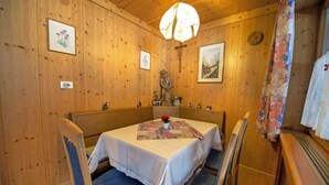 Puisesti sisustettu tila, jossa on ruokapöytä, jonka ääreen on katettu neljälle, ja pöydän ympärillä on tuoleja.