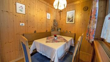 A wooden interior with a dining table set for four, surrounded by chairs.