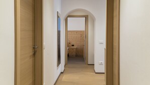 A hallway with wooden doors and a kitchen visible through an archway.