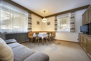 Une pièce confortable avec un canapé, une table à manger et des chaises, un téléviseur et un radiateur.