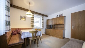 A cozy room with a wooden bench, a dining table with chairs, a television, and wooden cabinets. - Apartments Alara 134B (Ortisei)