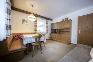 Una habitación acogedora con un banco de madera, una mesa de comedor con sillas, un televisor y armarios de madera.